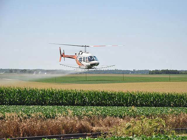 Andy Orr, AV8-ORR Helicopter Services, of Hamilton, Mont., sprays fungicides on tassel-stage corn at the Glen Haag farm, in Lewiston, Minn. (Progressive Farmer image by John Pocock)